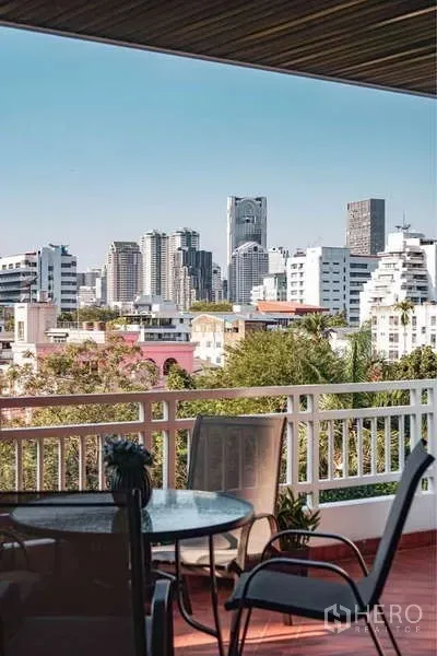 Apartment for rent in Sathon, Bangkok - Private balcony with outdoor table set overlooking Bangkok city skyline and leafy low-rise neighborhood.