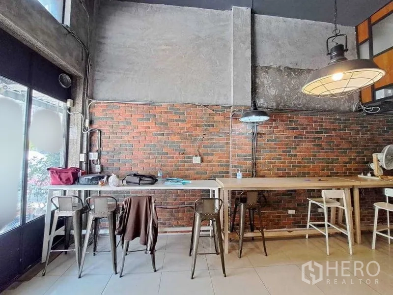 零售空间 出租在Khlong Toei, Bangkok - 沿砖墙的高吧台座位与吊灯，临近落地窗