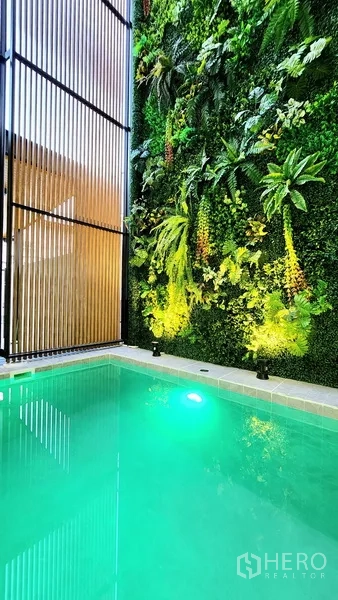 独立式住宅 出售在Khlong Toei, Bangkok - 泳池旁的垂直绿化墙特写，灯光映照。