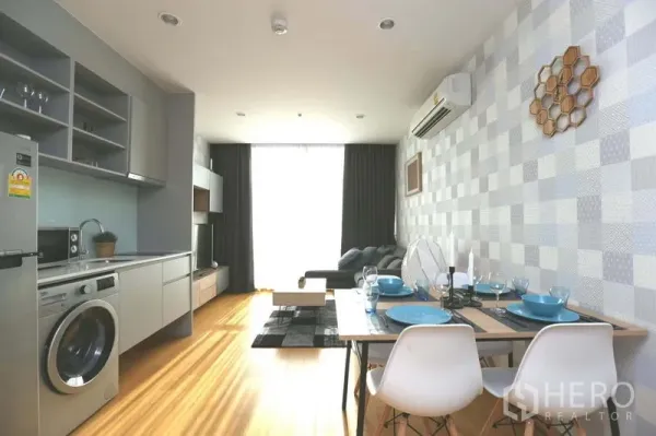 公寓 出售在Bang Rak, Bangkok - 开放式客餐厅与现代厨房，餐桌和沙发面向采光窗。