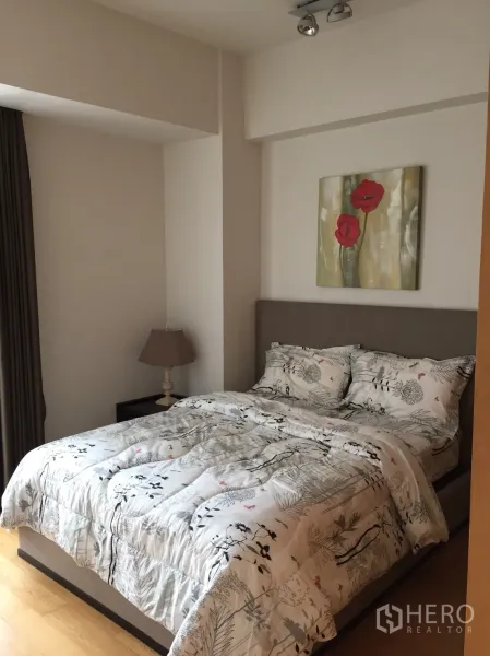 Condominium for rent or sale in Sathon, Bangkok - Cozy bedroom with upholstered bed, floral bedding and artwork on neutral walls.