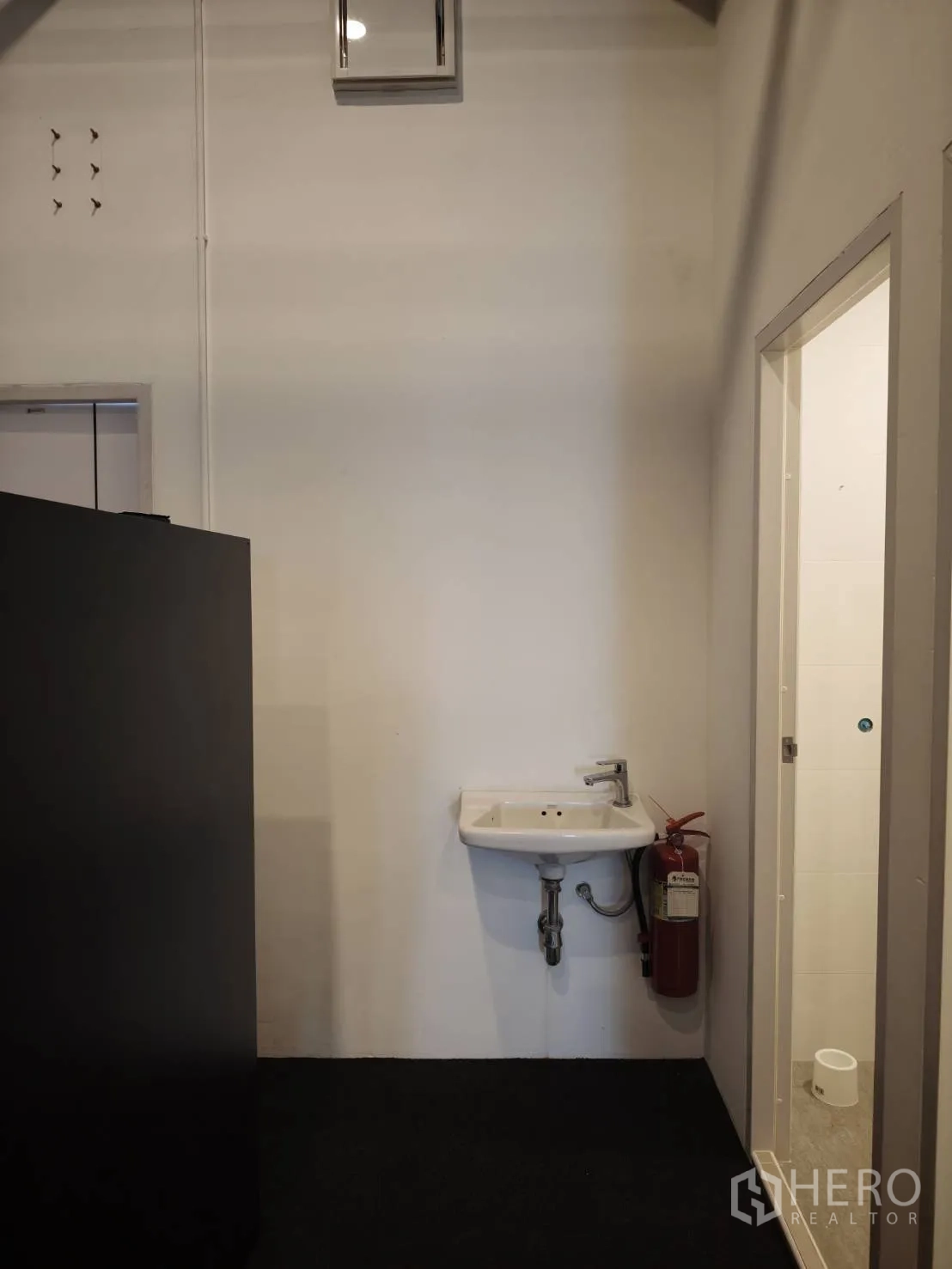 零售空间 for rent in Watthana, Bangkok - 壁挂洗手盆，旁有卫生间门与灭火器。