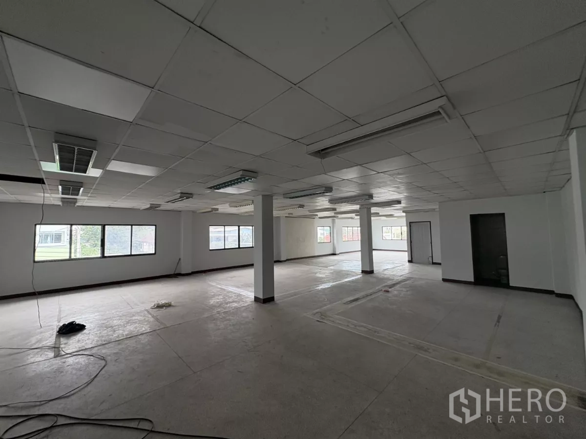 Factory for rent in Khlong Toei, Bangkok - Bright open office area with multiple windows and central columns.