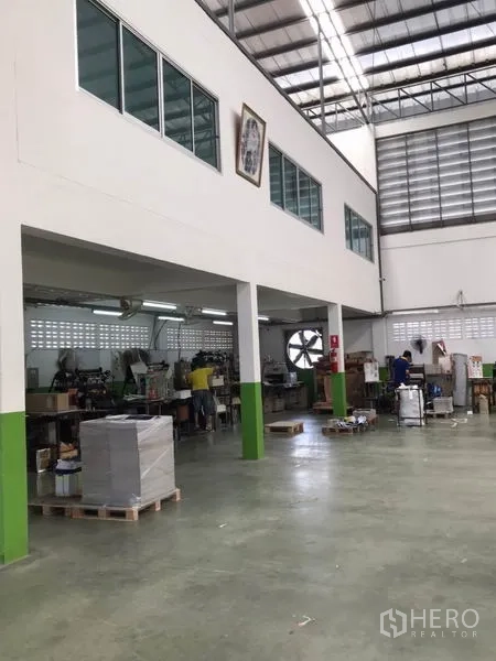 Factory for sale in Pak Kret, Nonthaburi - Warehouse interior showing mezzanine offices, high ceiling, and ventilation fans.