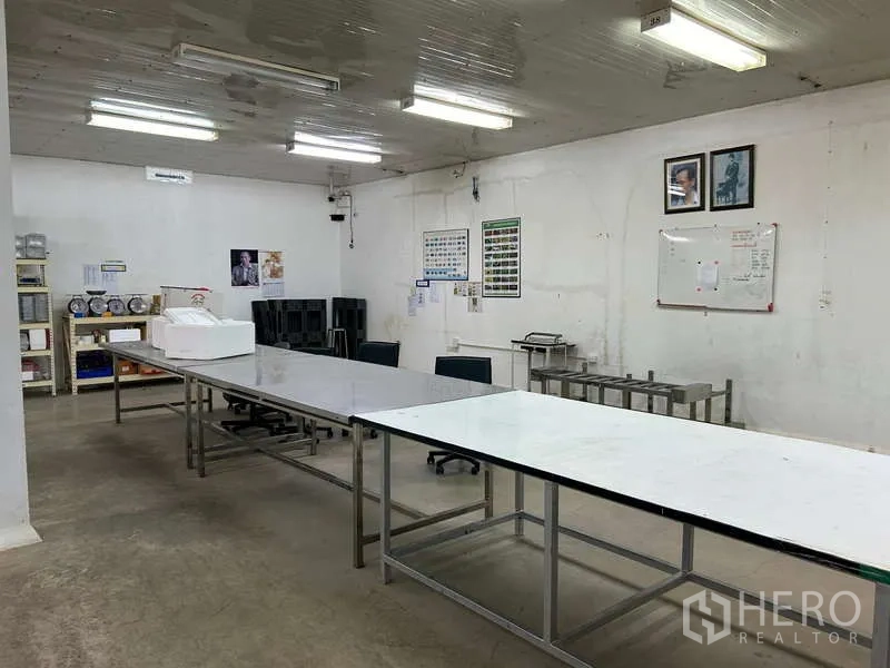 Warehouse for rent in Sam Phran, Nakhon Pathom - Preparation area with long stainless worktables, shelving and a whiteboard.