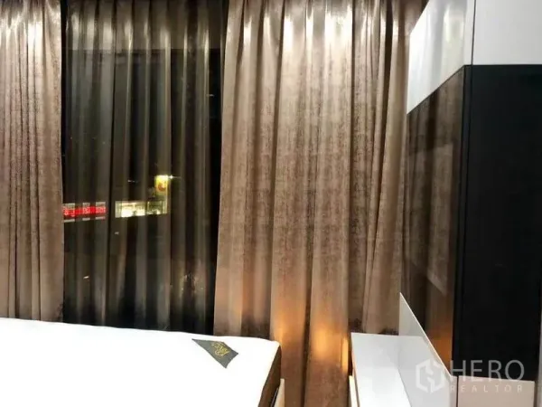 Condominium for rent or sale in Phaya Thai, Bangkok - Bedroom with floor-to-ceiling curtains and nighttime city lights outside the window.