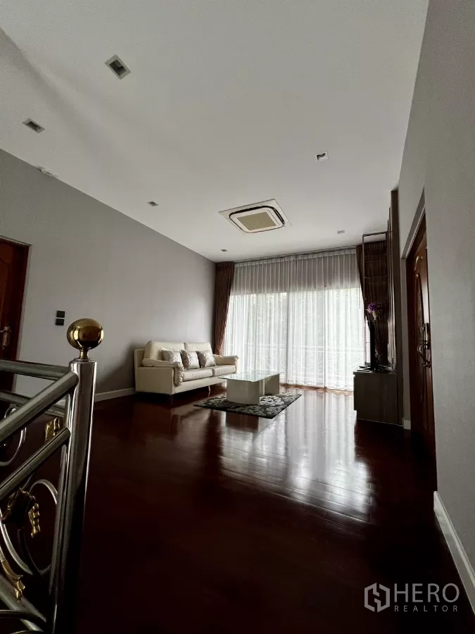 Detached House for rent or sale in Prawet, Bangkok - Upstairs family lounge with sofa and wide sliding glass doors to the balcony.
