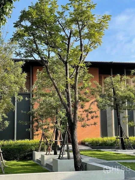 Detached House for sale in Sai Mai, Bangkok - Landscaped communal garden with mature trees and a brick-and-glass clubhouse.