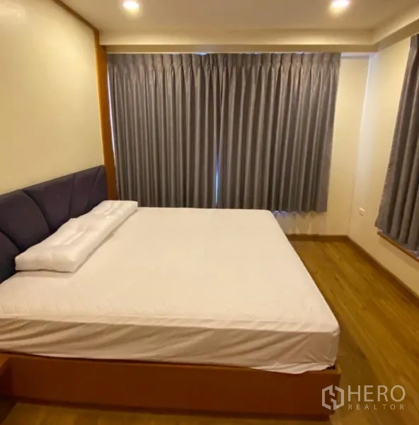Condominium for rent or sale in Sathon, Bangkok - Cozy bedroom with upholstered headboard, recessed lighting and blackout curtains.