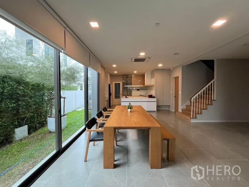 Detached House for rent or sale - Open-plan dining and kitchen with floor-to-ceiling windows facing a private garden and stairs.