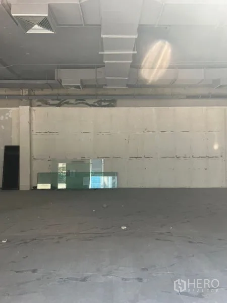 Retail Space for rent in Khlong Toei, Bangkok - Open-plan retail floor facing a blank wall with stacked glass panels beneath a ducted ceiling.