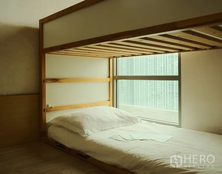 Condominium for rent in Bang Rak, Bangkok - Lower bunk bed facing large window with city view and natural light.
