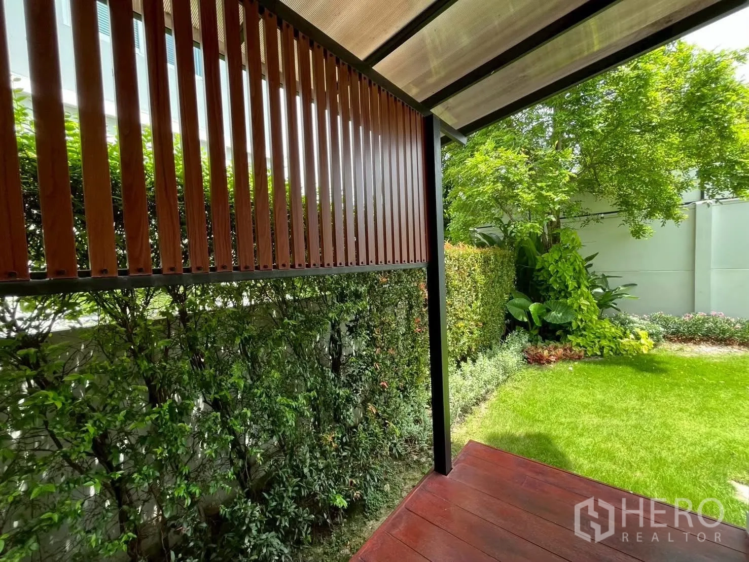 Detached House for rent in Prawet, Bangkok - Covered terrace with wood slat screen beside a landscaped garden.