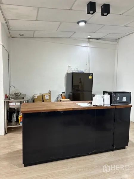 Shophouse for rent in Khlong Toei, Bangkok - Pantry area featuring a black counter with wooden top, refrigerator, microwave and sink.