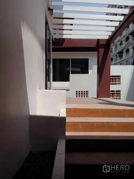 Detached House for rent in Phra Khanong, Bangkok - Front terrace with a pergola-style cover and steps leading to sliding doors.