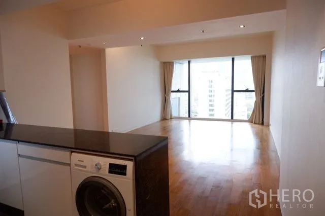 Condominium for sale in Sathon, Bangkok - Open kitchen counter with in-unit washer leading to living space and skyline window.