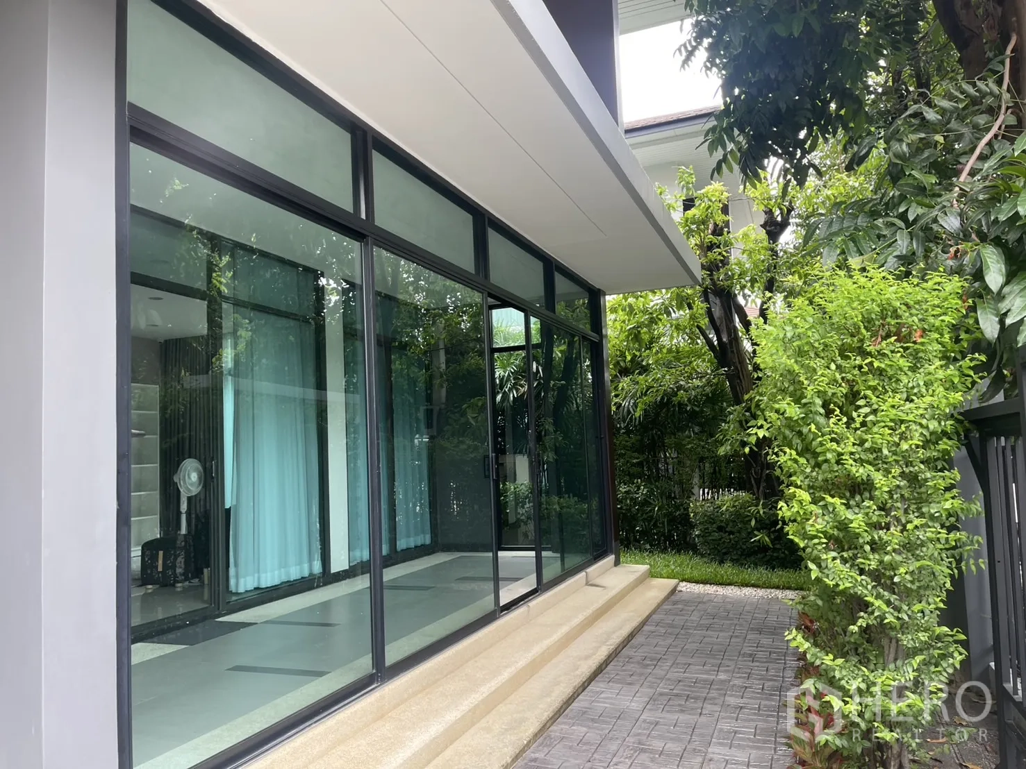 บ้าน ให้เช่าในBang Kapi, Bangkok - ด้านข้างตัวบ้านผนังกระจกบานใหญ่และทางเดินขอบพุ่มไม้