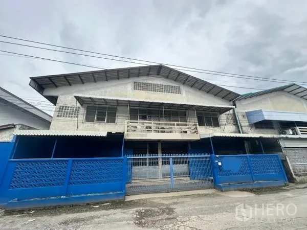 工厂 出租在Lam Luk Ka, Pathum Thani - 工厂正立面，蓝色围栏与滑动大门