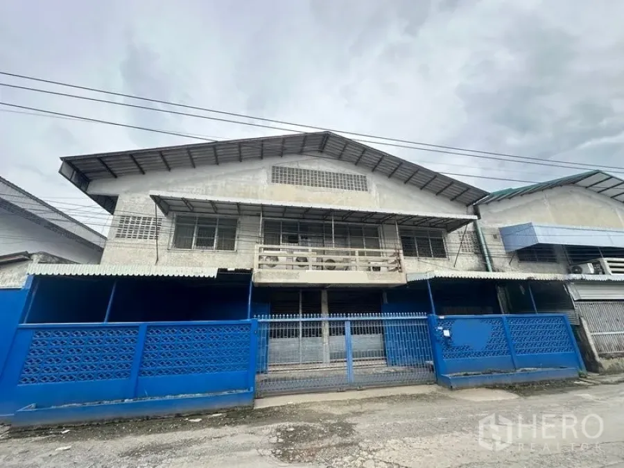工厂 出租在Lam Luk Ka, Pathum Thani - 工厂正立面，蓝色围栏与滑动大门