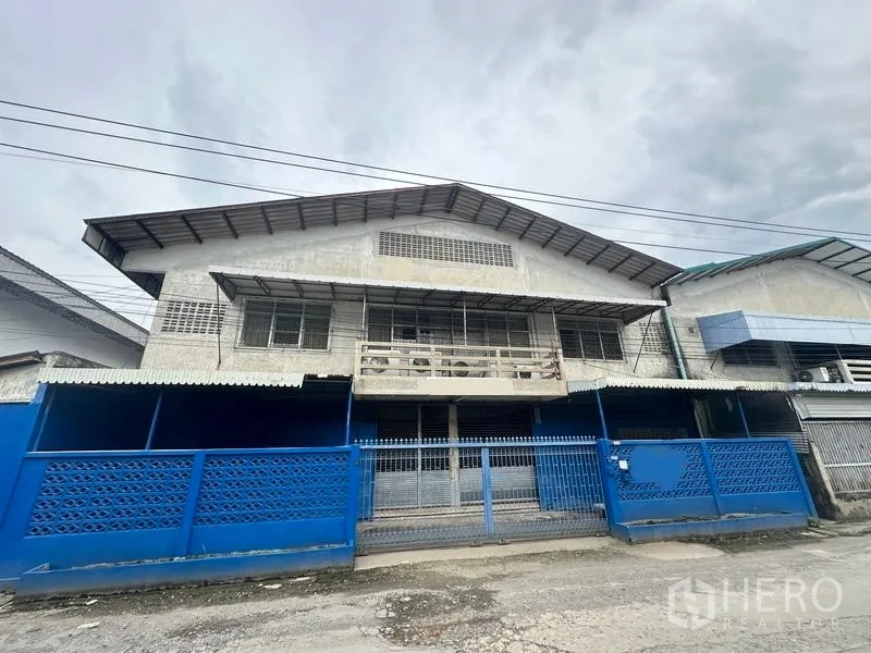 工厂 出租在Lam Luk Ka, Pathum Thani - 工厂正立面，蓝色围栏与滑动大门