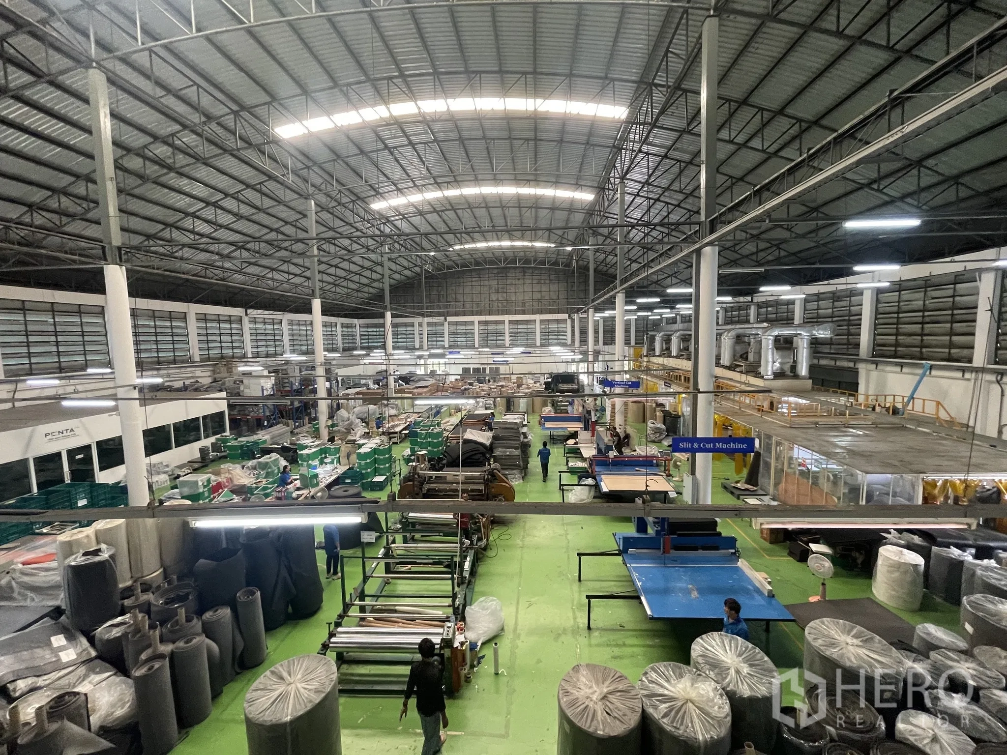 Warehouse for sale in Lat Lum Kaeo, Pathum Thani - Central aisle of the factory with cutting and slitting machines and overhead lighting.