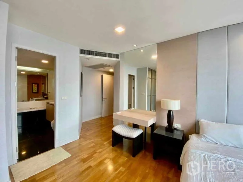 Condominium for rent or sale in Sathon, Bangkok - Bedroom corner with dressing table, bedside lamp, and doorway to bathroom.