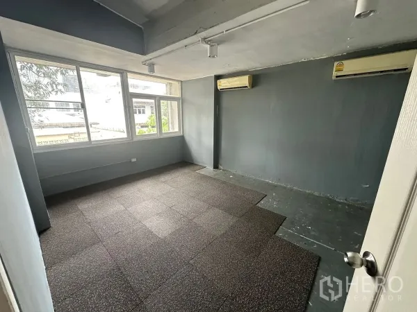 Home Office for rent in Chatuchak, Bangkok - Private office room with large windows, gray walls and wall-mounted air conditioners.