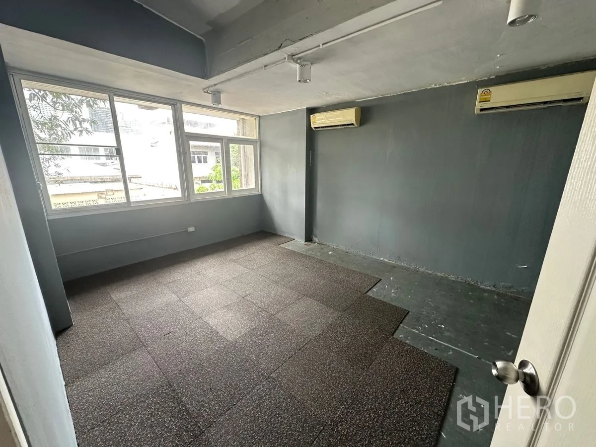 Home Office for rent in Chatuchak, Bangkok - Private office room with large windows, gray walls and wall-mounted air conditioners.