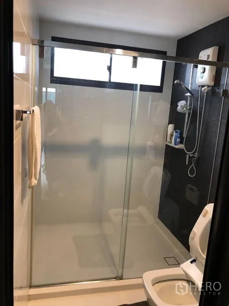 Townhouse for rent in Lat Phrao, Bangkok - Bathroom with wide frosted-glass sliding shower door, window and water heater.