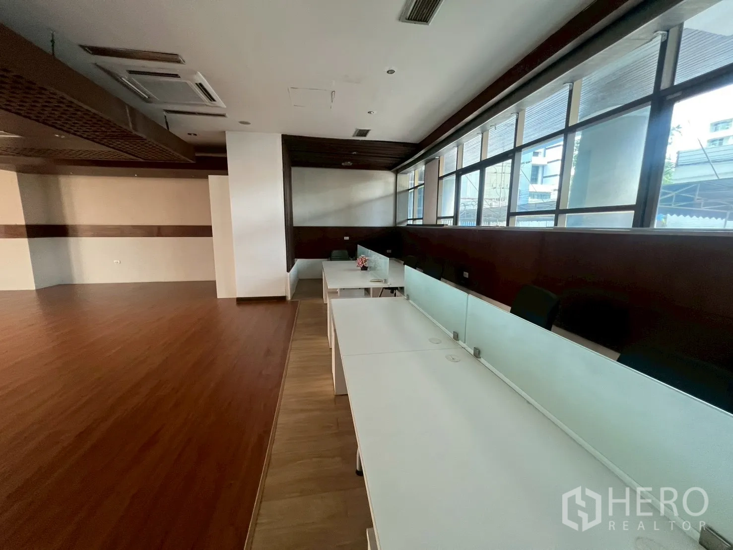 Retail Space for rent - Workstation row by large windows with white desks and frosted glass divider.