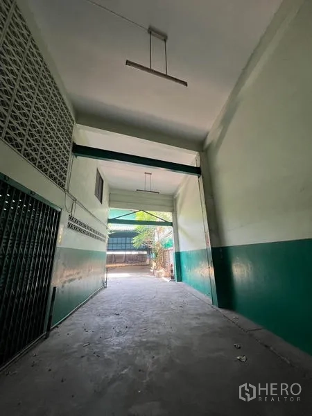 Warehouse for rent in Bang Kho Laem, Bangkok - High-clearance driveway tunnel leading to the rear yard, green-white walls.