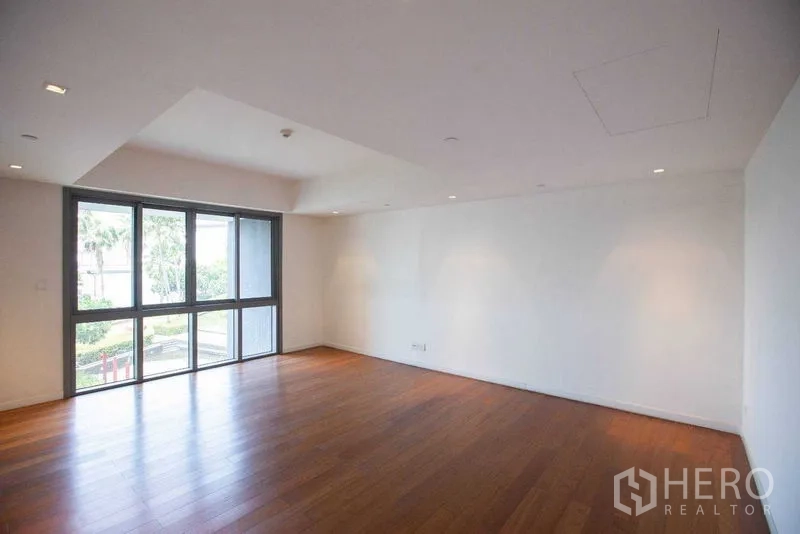 Condominium for rent in Yan Nawa, Bangkok - Spacious bedroom with wood floors and corner windows facing the garden.