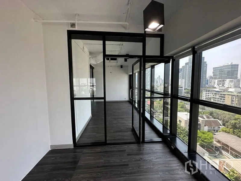 办公空间 出租 - 转角独立办公室，黑色框架玻璃墙，城市景观开阔。