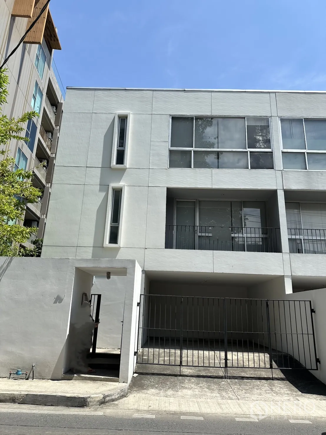 โฮมออฟฟิศ for rent in Phra Khanong, Bangkok - ด้านหน้าตัวอาคารโฮมออฟฟิศสีขาวสูงสามชั้นพร้อมทางเข้าประตูรั้วและระเบียง.