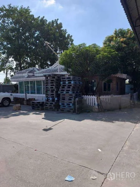 Warehouse for rent or sale in Khlong Toei, Bangkok - Outdoor concrete yard with trees and a small outbuilding, suitable for parking and maneuvering.
