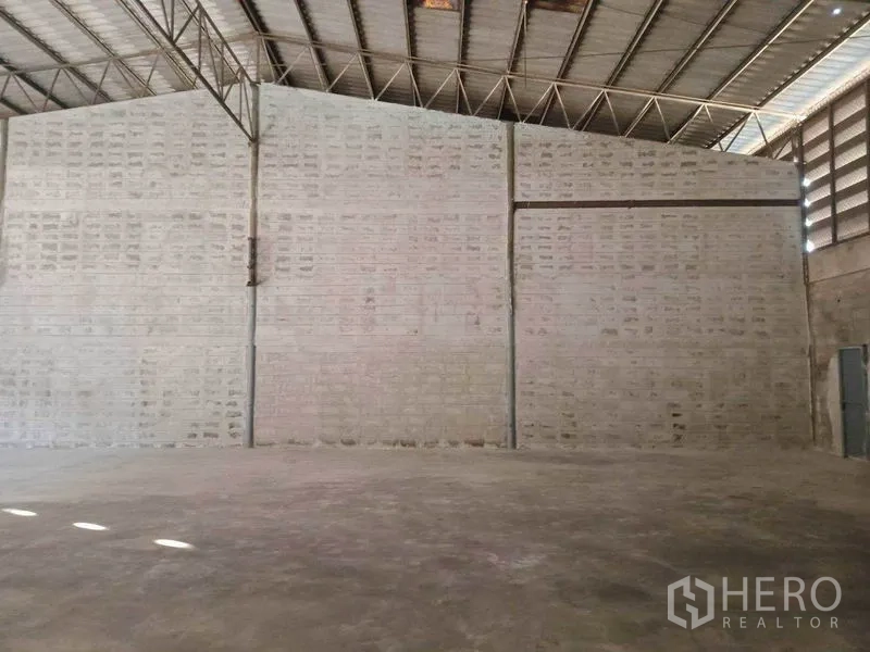 Warehouse for rent in Mueang Samut Sakhon, Samut Sakhon - High-ceiling warehouse showing steel truss roof and solid masonry walls.