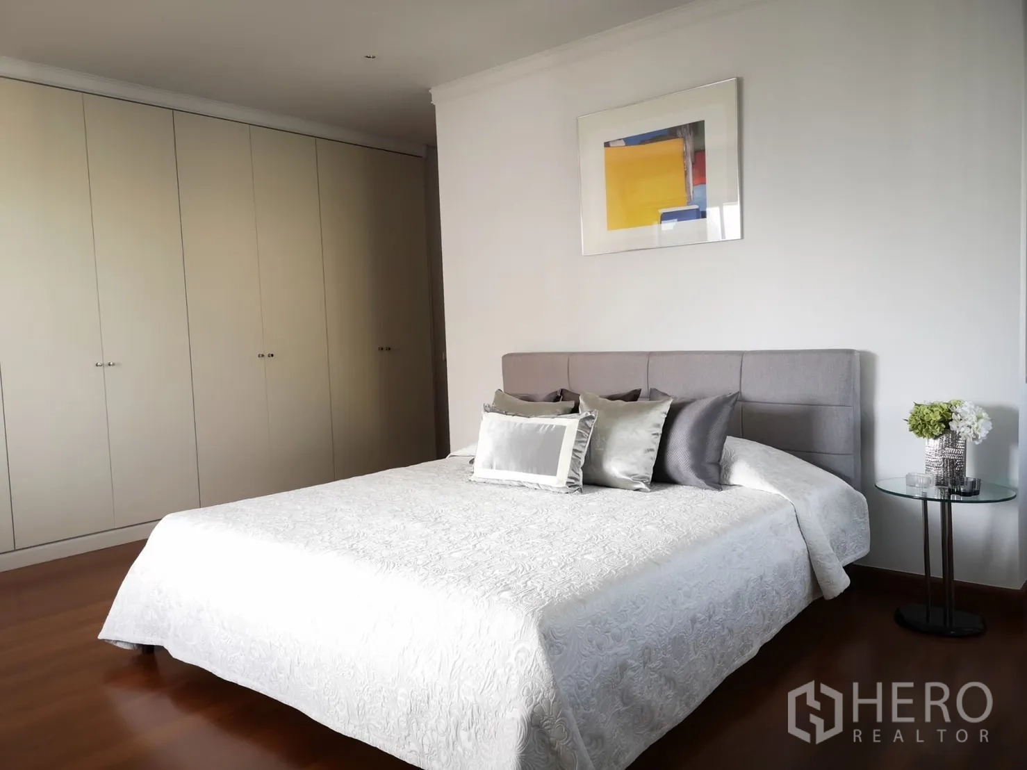 Condominium for rent in Bangkok - Bedroom with wall of wardrobes and minimalist decor.
