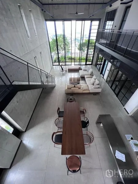 Condominium for rent in Sathon, Bangkok - Aerial view of dining table, living room and industrial staircase in a double-volume space.