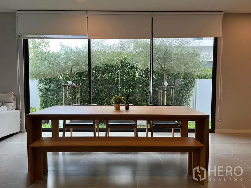 Detached House for rent or sale - Dining area with long wooden table and bench beside sliding glass doors overlooking greenery.