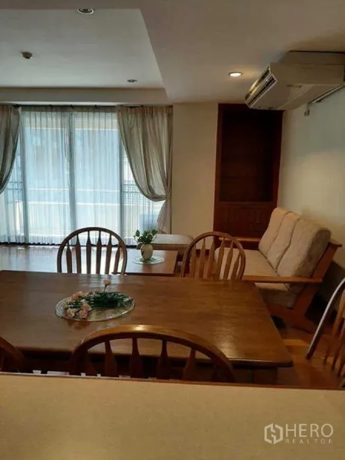 Apartment for rent in Watthana, Bangkok - Dining table by balcony windows with natural light and curtains.