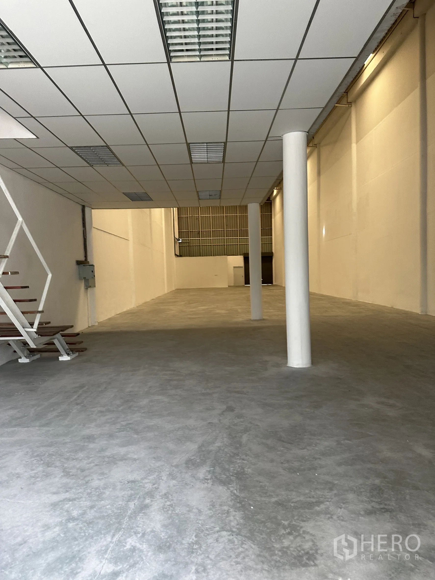 Factory for rent in Khlong Luang, Pathum Thani - Ground floor space beneath mezzanine with drop ceiling lights and smooth concrete floor.