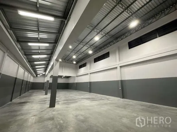 Factory for rent or sale in Bang Bua Thong, Nonthaburi - High-bay warehouse interior with steel truss roof and polished concrete floor.