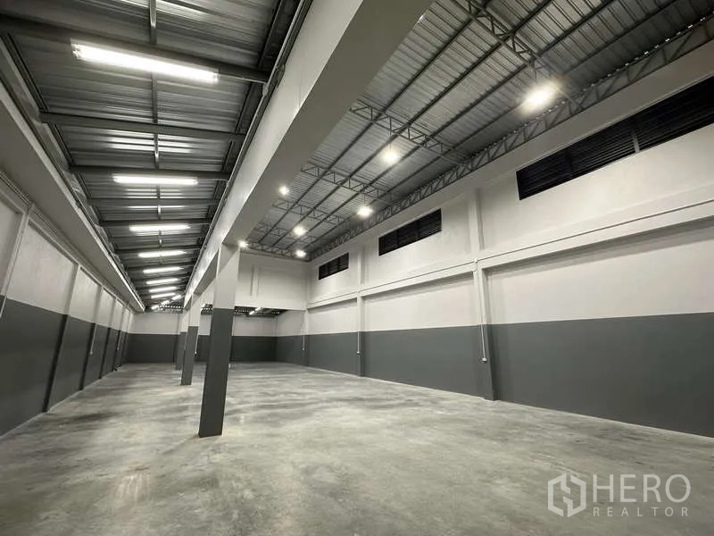 Factory for rent or sale in Bang Bua Thong, Nonthaburi - High-bay warehouse interior with steel truss roof and polished concrete floor.