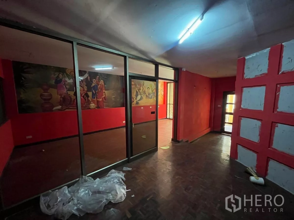 Shophouse for rent in Watthana, Bangkok - Open area divided by floor-to-ceiling glass partitions with mural artwork beyond.