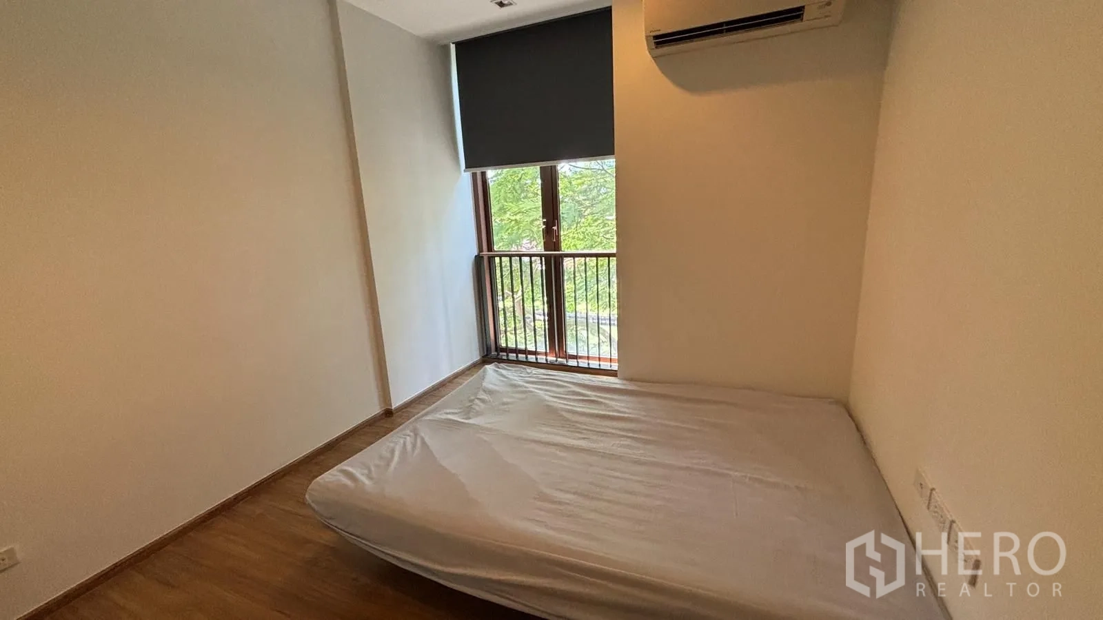 公寓 for rent or sale in Watthana, Bangkok - 卧室配双人床、卷帘与空调，窗外为树梢景观。