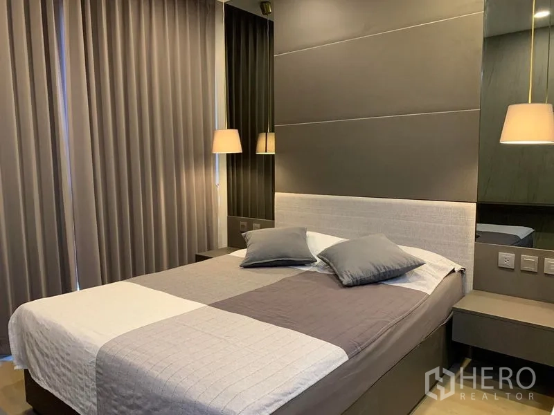 คอนโด ให้เช่าในBang Rak, Bangkok - ห้องนอนหลักเตียงควีน เฮดบอร์ดโทนเทา โคมแขวน และผ้าม่านสูงจรดเพดาน