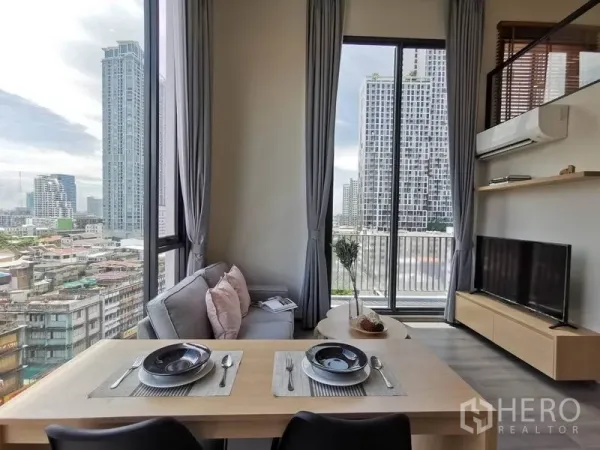 公寓 出租在Phaya Thai, Bangkok - 餐桌与沙发面向电视，推拉门通往阳台，眺望高楼。