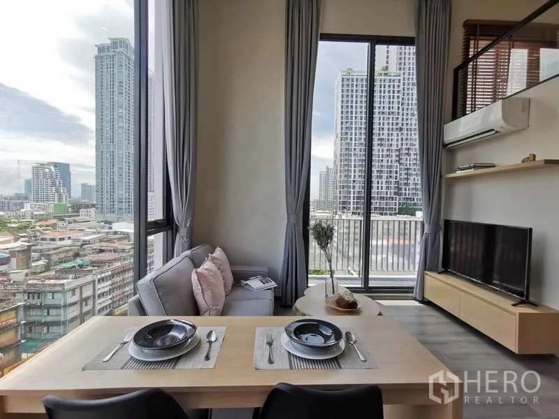公寓 出租在Phaya Thai, Bangkok - 餐桌与沙发面向电视，推拉门通往阳台，眺望高楼。