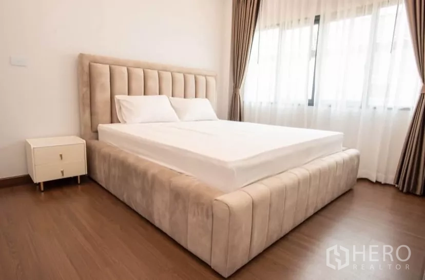 Detached House for rent in Bang Phli, Samut Prakan - Second bedroom with upholstered bedframe, sheer curtains and bedside table.