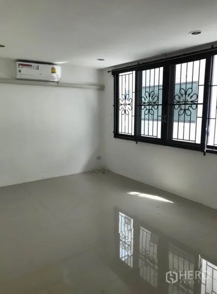 联排别墅 出租在Wang Thonglang, Bangkok - 明亮卧室，带防盗栏窗、白色墙面与壁挂空调。